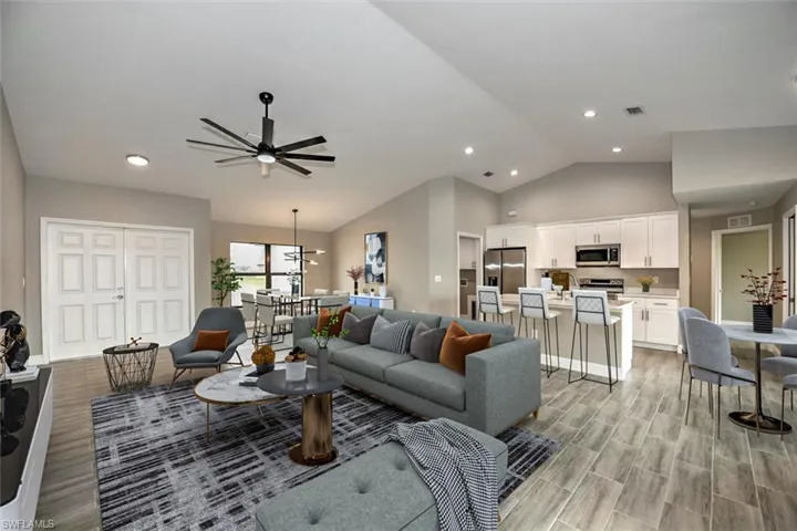Living room featuring high vaulted ceiling, ceiling fan, and light hardwood / wood-style floors