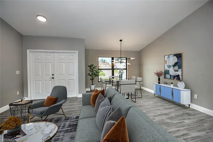 Living room featuring vaulted ceiling, hardwood / wood-style flooring, and a notable chandelier