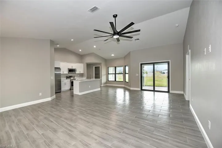 Unfurnished living room featuring sink, ceiling fan, vaulted ceiling, and light tile patterned floors