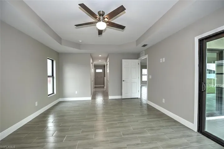 Tiled empty room with a tray ceiling and ceiling fan