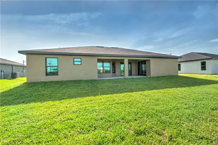 Back of property featuring a patio, central air condition unit, and a lawn