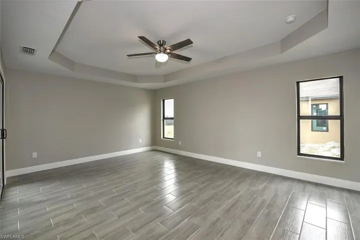 Unfurnished room with ceiling fan and a raised ceiling