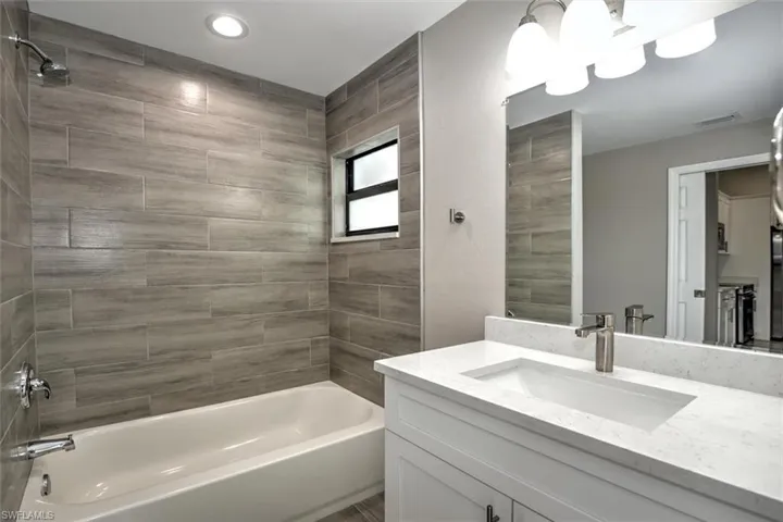 Bathroom with tiled shower / bath combo and vanity