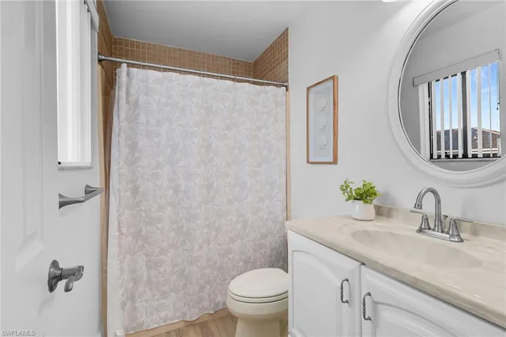 Full bath featuring curtained shower, vanity, and light wood-type flooring