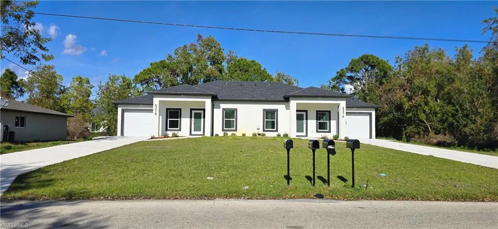 Prairie-style home with an attached garage, a front yard, stucco siding, and driveway