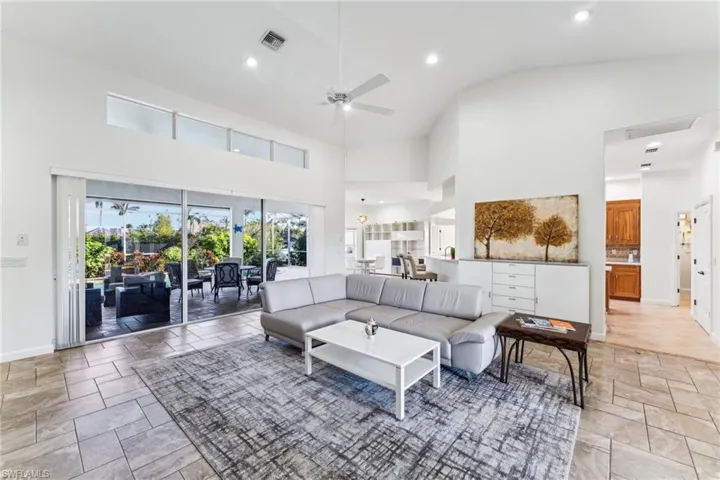 Living room featuring ceiling fan and high vaulted ceiling