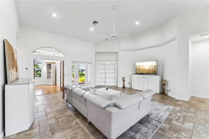 Living room with a towering ceiling, ceiling fan, and french doors