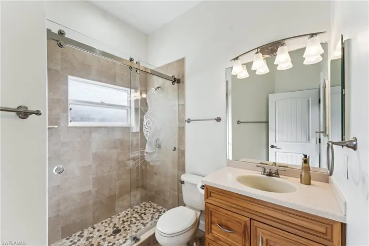 Bathroom featuring vanity, an enclosed shower, and toilet
