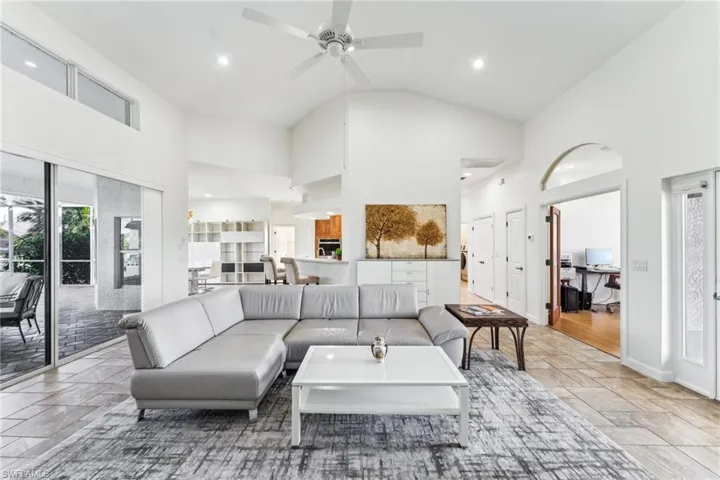 Living room featuring ceiling fan and high vaulted ceiling