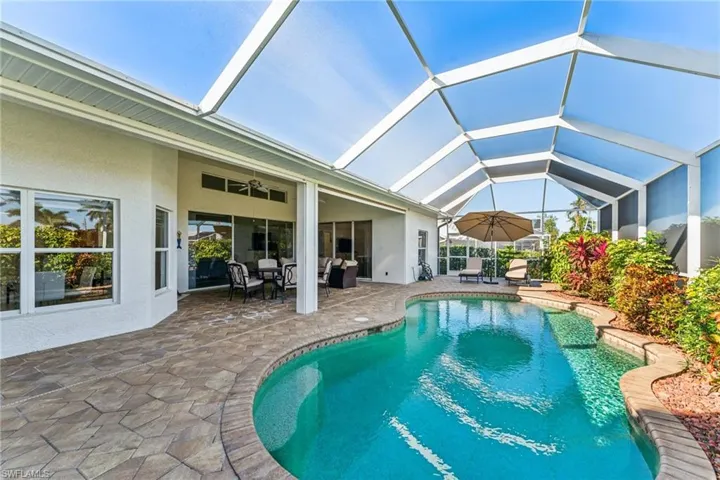 View of pool featuring a patio, outdoor lounge area, ceiling fan, and glass enclosure