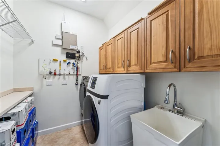 Laundry room featuring cabinets, sink, washing machine and dryer, and light tile patterned floors