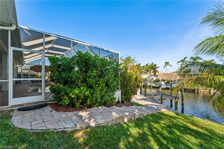 View of yard with a water view, glass enclosure, and a boat dock