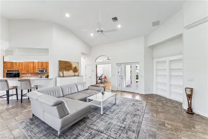 Living room featuring high vaulted ceiling, french doors, and ceiling fan