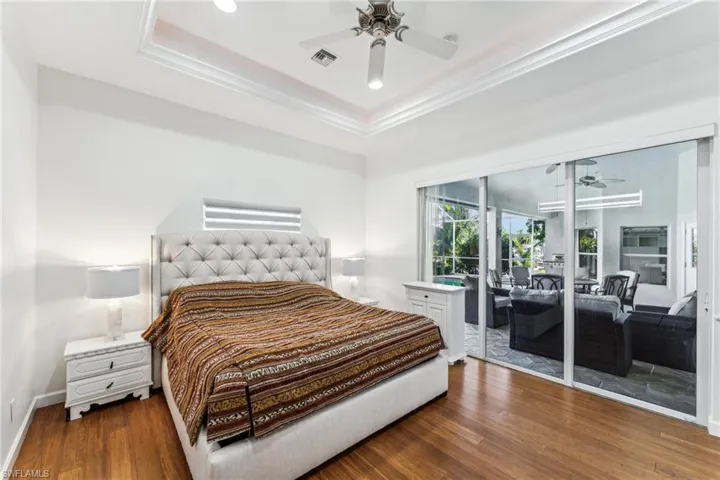 Bedroom with ornamental molding, dark hardwood / wood-style floors, access to exterior, and a tray ceiling