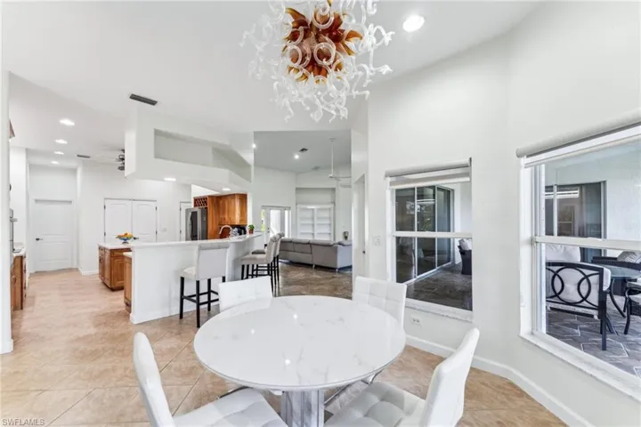 Tiled dining area with ceiling fan with notable chandelier