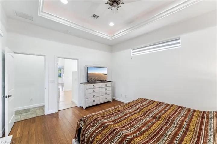 Bedroom with hardwood / wood-style flooring, a raised ceiling, and ceiling fan
