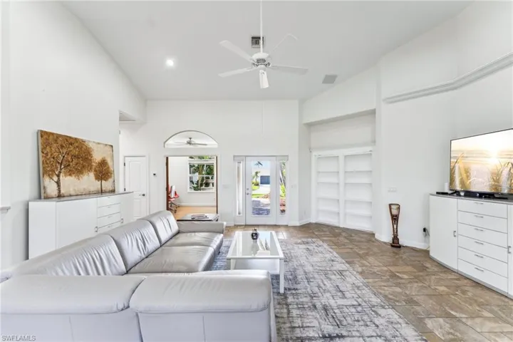 Living room featuring a high ceiling, ceiling fan, and built in shelves