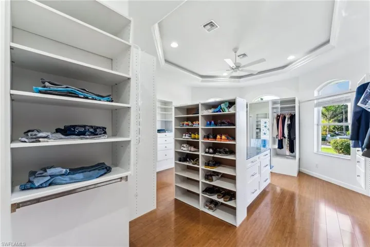 Spacious closet featuring ceiling fan, a raised ceiling, and hardwood / wood-style floors