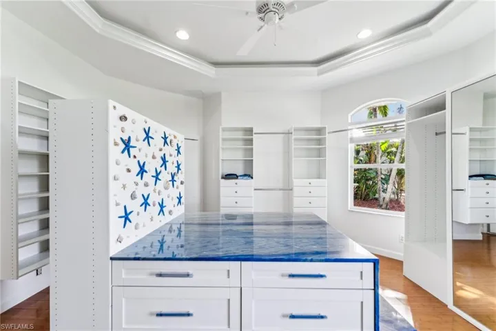 Kitchen with white cabinetry, hardwood / wood-style flooring, a raised ceiling, and ceiling fan
