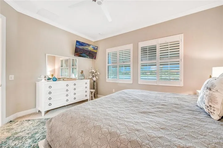 Carpeted bedroom with ornamental molding and ceiling fan