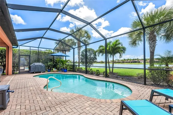 View of pool featuring a patio area, glass enclosure, and a water view