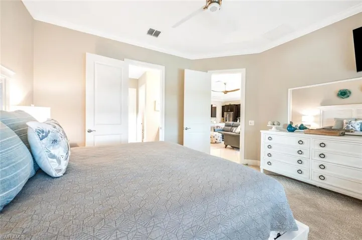 Carpeted bedroom with ceiling fan and crown molding
