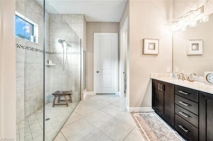 Bathroom featuring tile patterned floors, a shower with shower door, and vanity