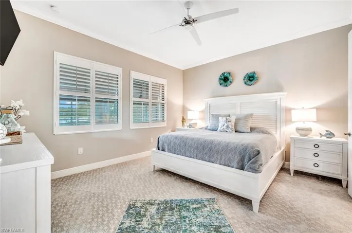 Carpeted bedroom featuring ceiling fan and crown molding