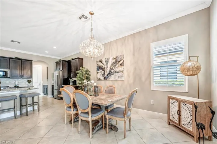 Tiled dining area with crown molding and a chandelier