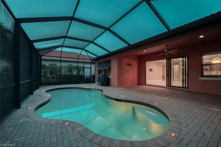 Outdoor pool with a patio area, a ceiling fan, and glass enclosure