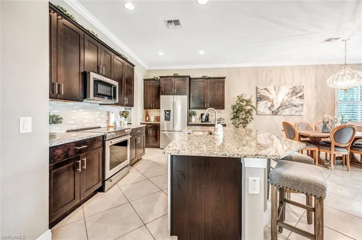 Kitchen featuring a breakfast bar area, light stone countertops, a kitchen island with sink, stainless steel appliances, and sink