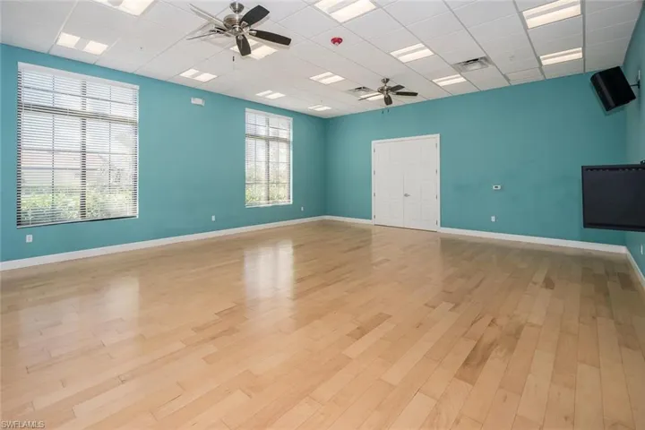 Spare room featuring light wood-type flooring, a paneled ceiling, ceiling fan, and a healthy amount of sunlight