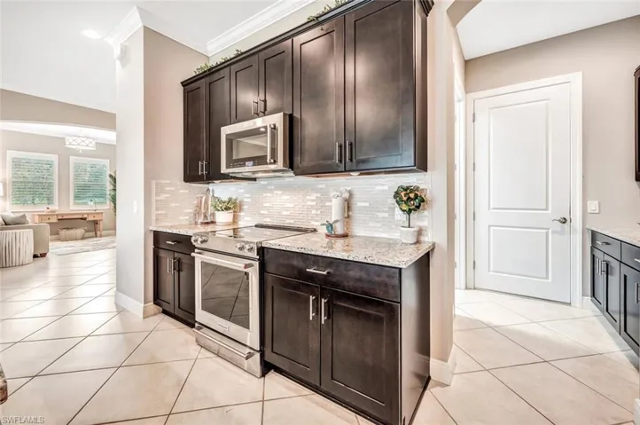Kitchen featuring light stone counters, stainless steel appliances, and dark brown cabinetry