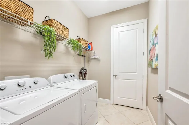 Laundry area with washing machine and dryer and light tile patterned floors
