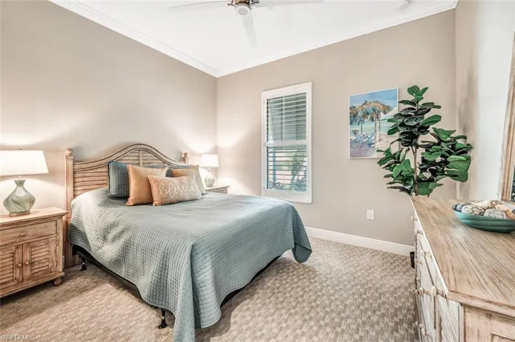 Bedroom with light carpet, ornamental molding, and ceiling fan