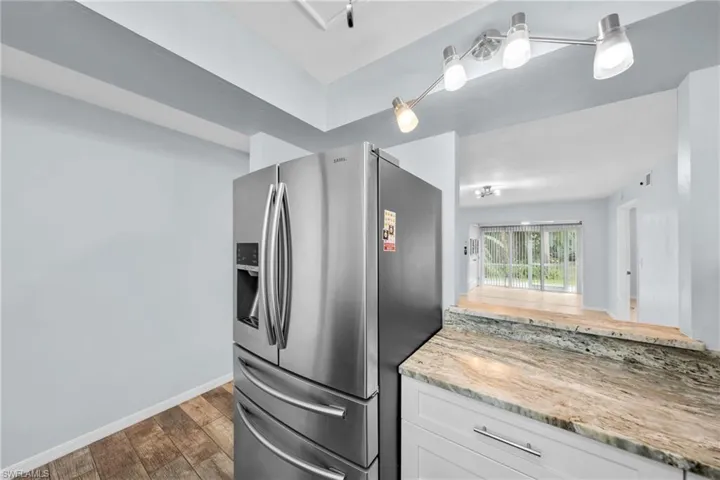 Stainless steel French door refrigerator with an ice and water dispenser, complemented by a stone countertop and white cabinetry