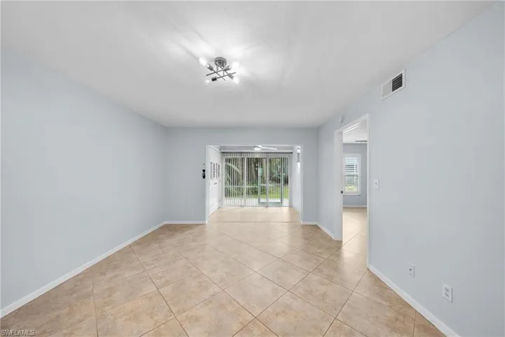 Spacious interior room featuring light-colored tile flooring, neutral wall paint, and a modern ceiling light fixture