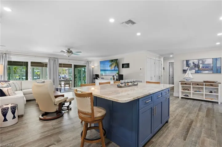 Kitchen with blue cabinets, a kitchen island, open floor plan, and wood finished floors. Virtually Edited Image