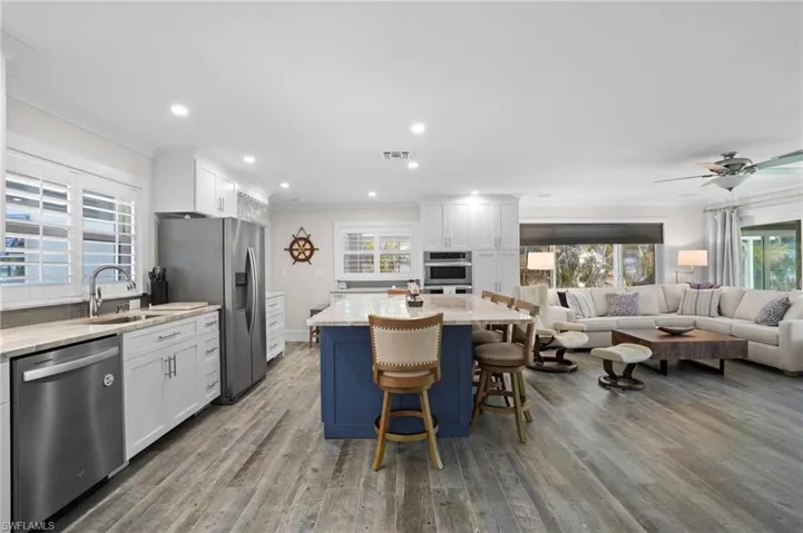 Kitchen with stainless steel appliances, open floor plan, crown molding, and a sink. Virtually Edited Image