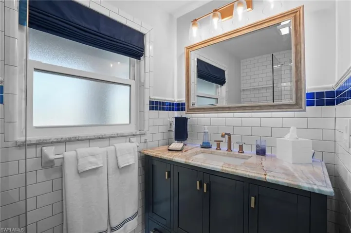 Bathroom featuring vanity and tile walls. Virtually Edited Image