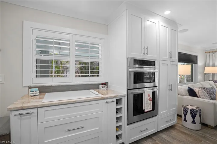 Kitchen with a healthy amount of sunlight, white stovetop, double oven, and white cabinetry. Virtually Edited Image