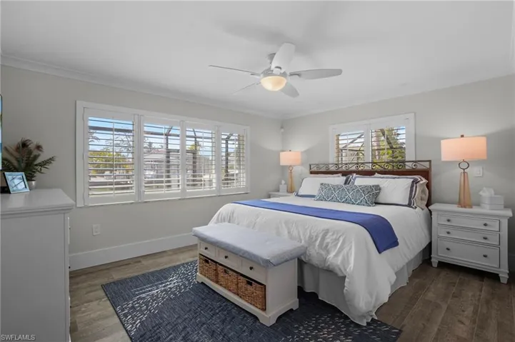 Bedroom with ceiling fan, crown molding, baseboards, and wood finished floors. Virtually Edited Image