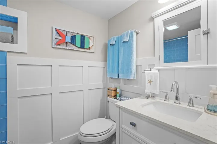 Full bathroom featuring wainscoting, vanity, toilet, and a decorative wall. Virtually Edited Image