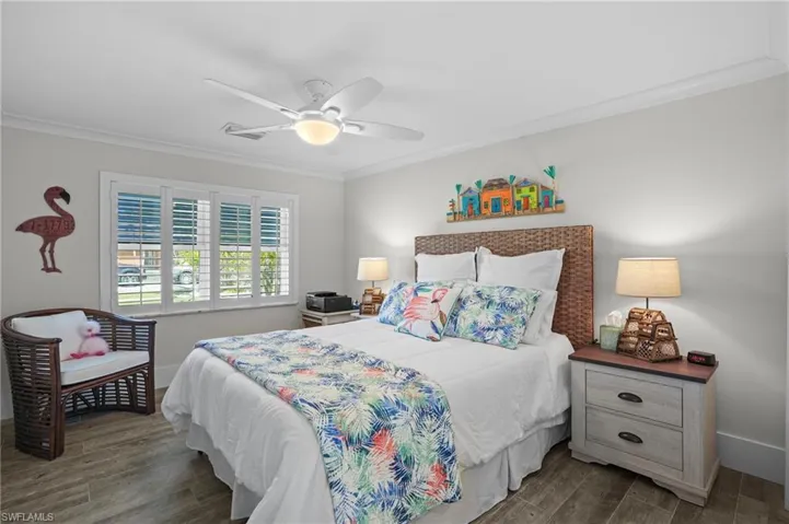 Bedroom with ornamental molding, dark wood-type flooring, baseboards, and a ceiling fan. Virtually Edited Image