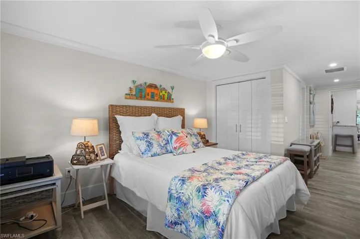 Bedroom with ornamental molding, a closet, wood finished floors, and visible vents. Virtually Edited Image