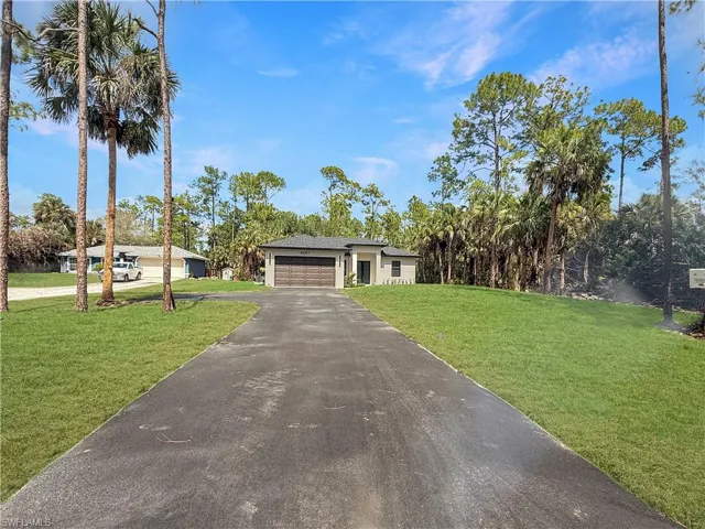 View of front of home with a front yard, asphalt driveway, and an attached garage