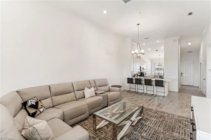 Living room featuring recessed lighting, wood finish floors, a chandelier, and ornamental molding