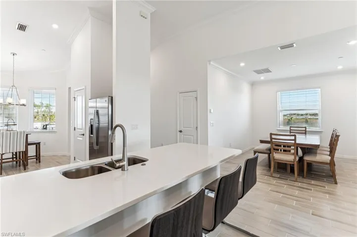 Kitchen featuring wood tiled floors, healthy amount of natural light, recessed lighting, stainless steel fridge, and ornamental molding