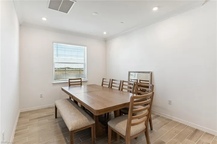 Dining room with wood tiled floors, crown molding, and recessed lighting