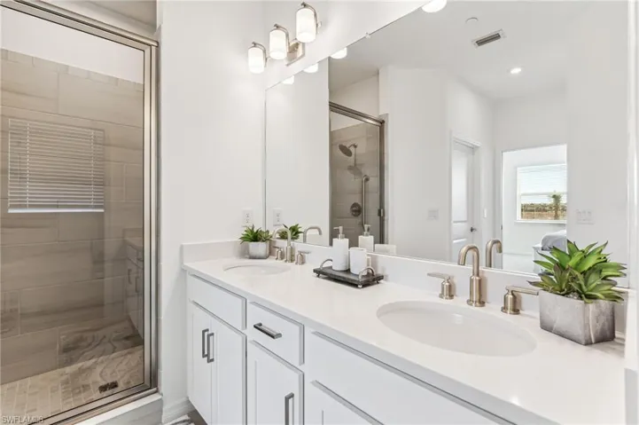 Full bath featuring double vanity and a shower stall